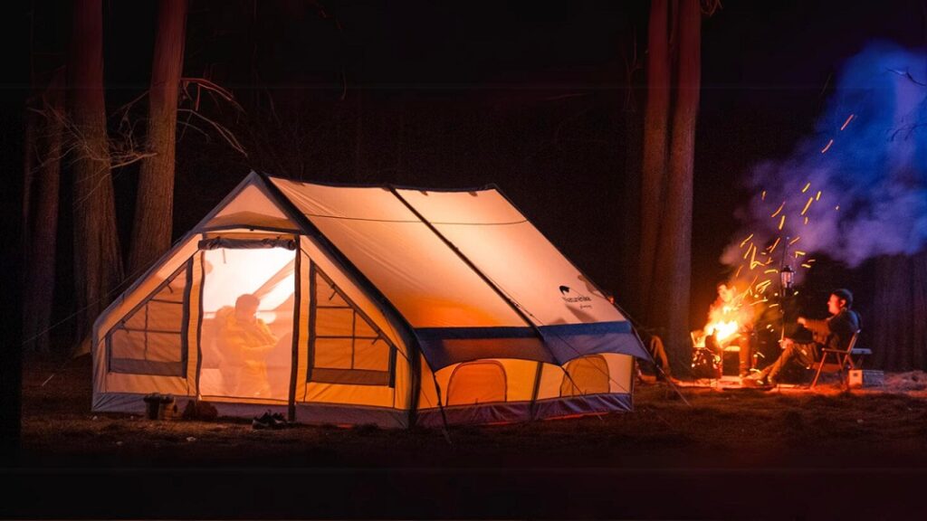 A group of people enjoying a night by setting up a bonfire next to an inflatable tent house.
